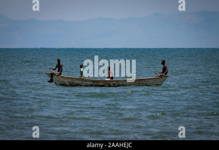 Pescatore sul lago Malawi che viaggiano in una barca tradizionale, con il Mozambico montagne sullo sfondo Foto Stock