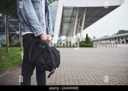 Giovane uomo bello con un sacchetto sulla sua spalla in fretta all'aeroporto. Foto Stock