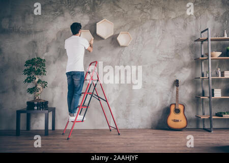 A piena lunghezza dietro posteriore guarda foto di razza mista arabian guy installazione Mensola a muro in piedi sulla scala la riparazione del nuovo piano di lavoro artigiano appeso Foto Stock