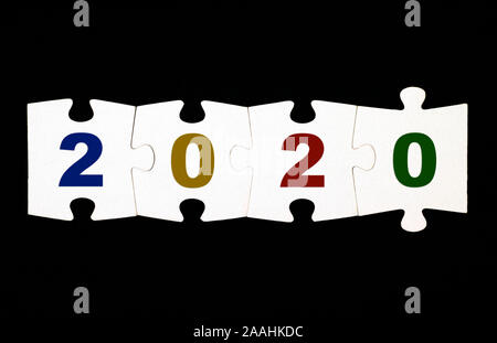 Quattro pezzi di un puzzle con i numeri 2020 sono collegati insieme su sfondo nero Foto Stock