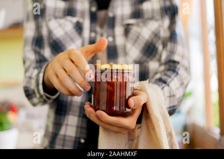 La persona tenuta a mano a casa un vasetto di marmellata di frutta, vasi di vetro, Foto Stock