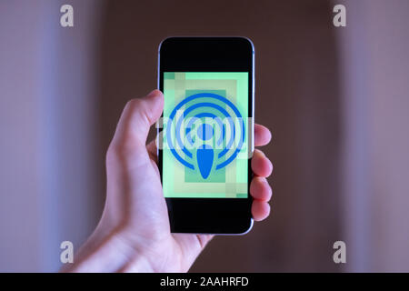 Mano che tiene uno smartphone con il podcast icona applicazioni Foto Stock