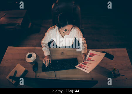 Parte superiore al di sopra di un angolo alto vista di lei bella attraente ed elegante intelligente smart sperimentato lady banchiere finanziere economista report di analisi reddito utile Foto Stock