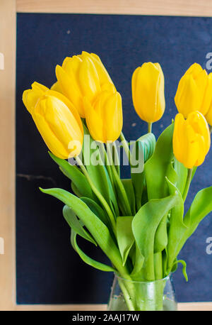 Un mazzo di tulipani gialli su una lavagna sfondo Foto Stock
