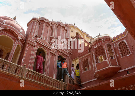 Jaipur, Rajasthan, India: la facciata interna del palazzo dei venti (Hawa Mahal) con alcune persone di fronte a un balcone Foto Stock