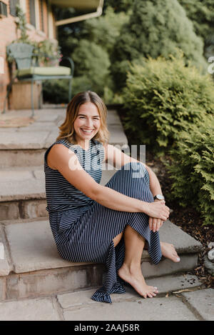 Felice donna seduta su giardino passi Foto Stock