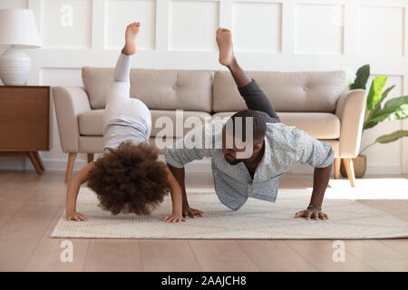 Felice biracial papà e figlia fare ginnastica mattutina a casa Foto Stock