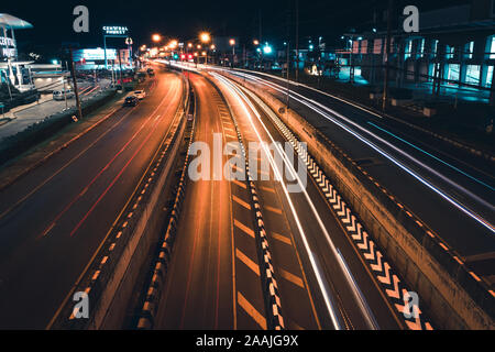 Phuket - Thailandia, 21 Novembre 2019 : il traffico su strada di notte per il traforo stradale tra il centro commerciale per lo shopping presso il Central festival. Una lunga esposizione auto luce Foto Stock