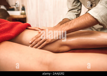 Medicina alternativa. Terapeuta donna di guarigione facendo massaggi ayurvedici applicazione di olio sulle gambe di close-up Foto Stock