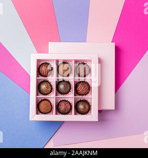 Cioccolatini impostato in un riquadro rosa su carta colorata sullo sfondo. Appartamento vista dall'alto. Copia dello spazio. Concetto di vacanza minimalismo. Cornice quadrata Foto Stock