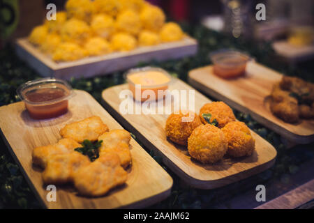 Gruppo di sfera di formaggio sul piatto di legno con un altro snack fritti accanto Foto Stock