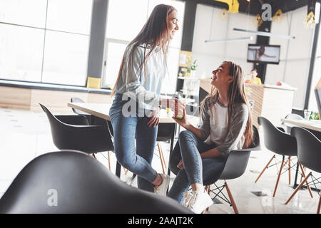 Due belle figlie gemelle dedicare tempo a bere il succo. Sorelle rilassante in un cafe e divertirsi insieme Foto Stock