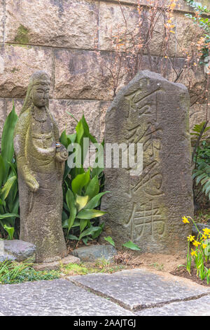 Statua di Pietra di Buddha Amitabha e il suo nome inciso in ideogrammi giapponesi su un monumento di pietra nel tempio Choanji in Tokyo. Foto Stock