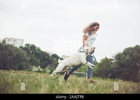 Una giovane ragazza sorridente con una felice espressione felice gioca con il suo amato cane. Foto Stock