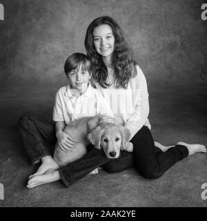 Ritratto di fratello e sorella con il Golden Retriever cucciolo Foto Stock