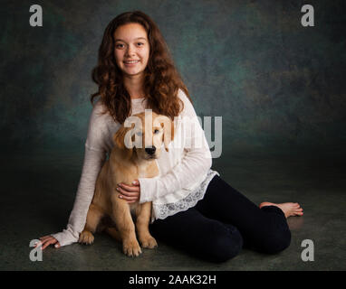 Ritratto in studio della ragazza adolescente con il Golden Retriever cucciolo Foto Stock