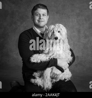 Ritratto in studio di uomo con Mini Golden Doodle Foto Stock