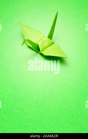 Green origami bird su sfondo verde Foto Stock