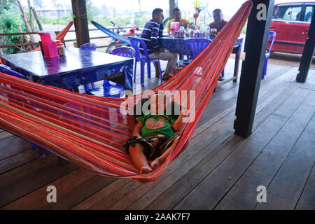 Ristorante a bordo strada in Kratie, Cambogia. Il bambino dorme in amaca. Foto Stock
