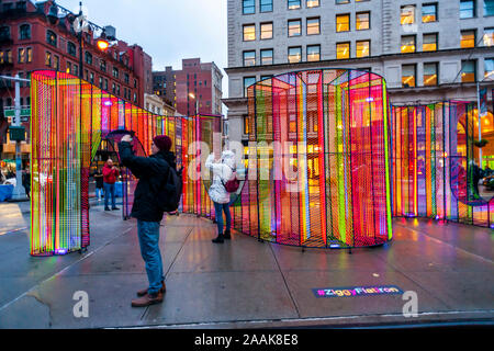 I visitatori di Flatiron Plaza di New York Lunedì, Novembre 18, 2019 interagiscono con ÒZiggyÓ creato da Hou de Sousa. L'installazione di Natale è il fulcro del Flatiron/23rd Street del Partenariato per la programmazione di vacanza, Ò23 Giorni di Flatiron CheerÓ. ÒZiggyÓ contiene 27.000 piedi di cavo iridescenti illuminati dalla luce UV. (© Richard B. Levine) Foto Stock