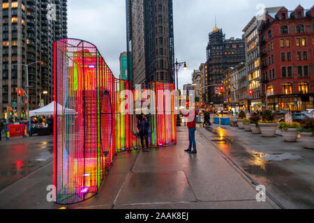 I visitatori di Flatiron Plaza di New York Lunedì, Novembre 18, 2019 interagiscono con ÒZiggyÓ creato da Hou de Sousa. L'installazione di Natale è il fulcro del Flatiron/23rd Street del Partenariato per la programmazione di vacanza, Ò23 Giorni di Flatiron CheerÓ. ÒZiggyÓ contiene 27.000 piedi di cavo iridescenti illuminati dalla luce UV. (© Richard B. Levine) Foto Stock