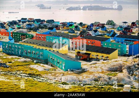 Case colorate in Illulisat con gli iceberg nella baia. Foto Stock