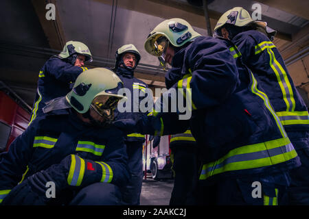 Ritratto di gruppo di vigili del fuoco che indossano uniformi di protezione all'interno della stazione dei vigili del fuoco Foto Stock