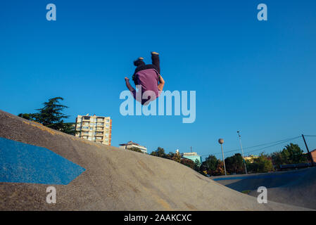 Acrobatico giovane ragazzo che fa parkour allenamento presso il parco giochi di skate Foto Stock
