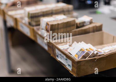 Grande quantità di contanti divisi e ordinati con bande di valuta e posti in scatole di cartone Foto Stock