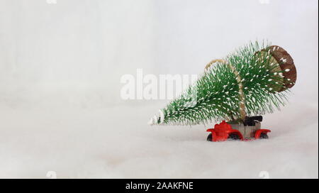 Giocattolo auto portante un albero di Natale in un paesaggio innevato. Spazio per il testo. Foto Stock