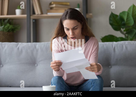 Scioccato giovane donna sbalordita dalle cattive notizie per lettera Foto Stock