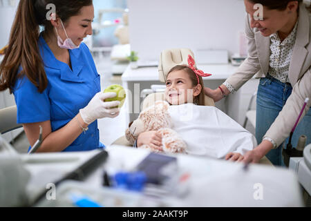 Giovane ragazza sorridente durante la procedura dentale con il dentista Foto Stock