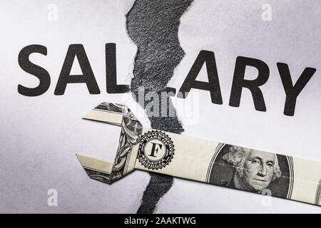 Un foglio di carta bianco con le parole lo stipendio è strappata a metà. Il concetto di crisi finanziaria. I bassi salari che richiede la regolazione Foto Stock
