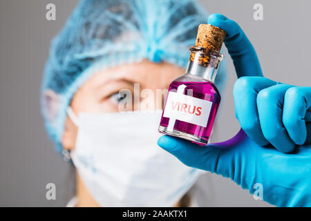 Il medico in laboratorio può contenere una bottiglia con il virus nelle sue mani. Concetto sulla fabbricazione illecita di sostanze tossiche. Virus pericoloso Foto Stock