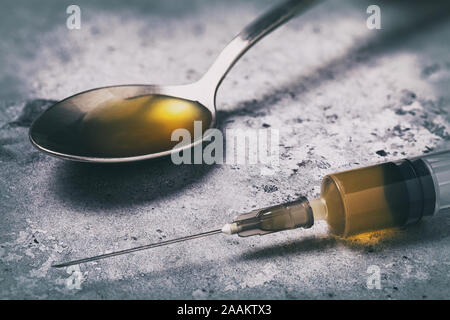 Il farmaco è il nemico del mondo moderno. Farmaci in una siringa e il cucchiaio sul tavolo, close-up Foto Stock
