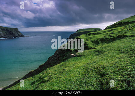 Vista panoramica con bassa appendere le nubi della costiera irlandese situato vicino a Malin Beg, una baia isolata con ripide scogliere circondato da lussureggianti colline verdi. Foto Stock