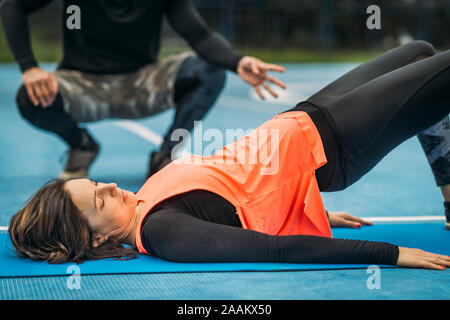 Giovane donna sportivo esercitando all aperto con personal trainer. Foto Stock