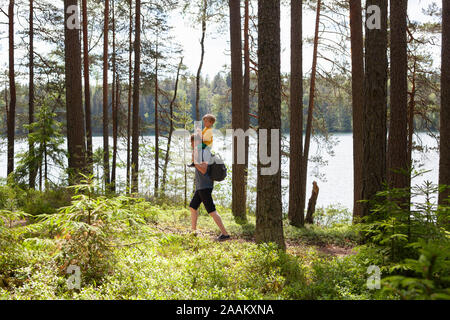 Padre dando figlio piggyback ride in foresta, Finlandia Foto Stock
