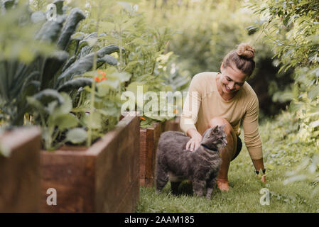 Donna giardiniere con gatto in giardino Foto Stock