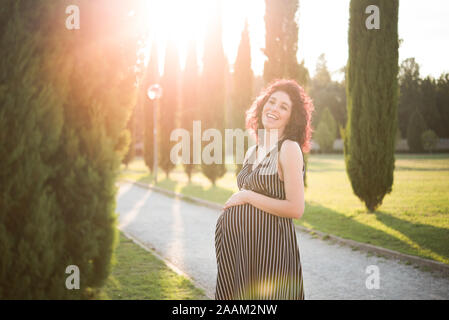 Donna incinta mano appoggiata sulla pancia in posizione di parcheggio Foto Stock