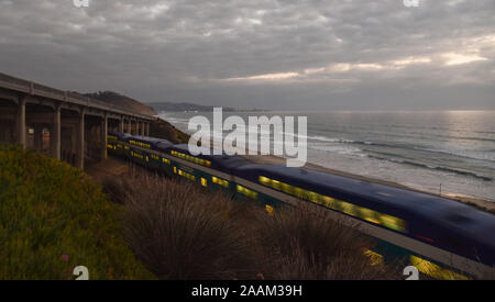 Coaster passeggero locomotiva diesel viaggi costieri lungo i binari della ferrovia sotto il ponte, nuvoloso, vicino a Torrey Pines Park, La Jolla, California, Stati Uniti d'America Foto Stock