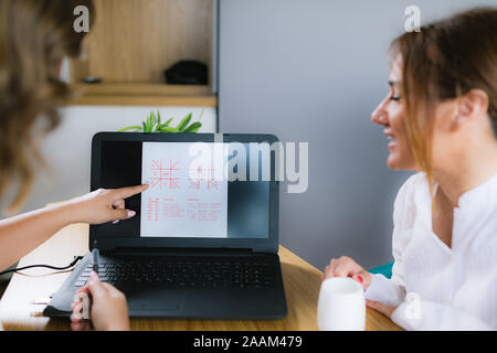 L'astrologia vedica jyotisha consultazione. Udienza dalla scrivania nella parte anteriore del computer portatile e guardando a Natal grafico. Foto Stock