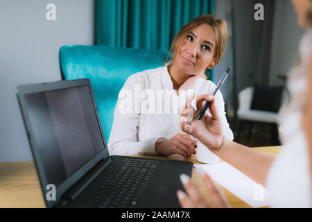 L'astrologia vedica jyotisha consultazione. Udienza dalla scrivania nella parte anteriore del computer portatile e guardando a Natal grafico. Foto Stock