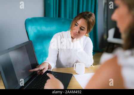 L'astrologia vedica jyotisha consultazione. Udienza dalla scrivania nella parte anteriore del computer portatile e guardando a Natal grafico. Foto Stock