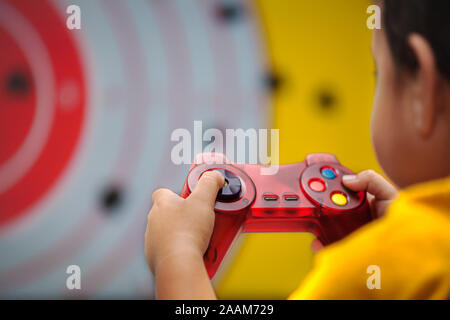 Giovane ragazzo in possesso di un gamepad generico durante la riproduzione di un violento genere video gioco. Foto Stock