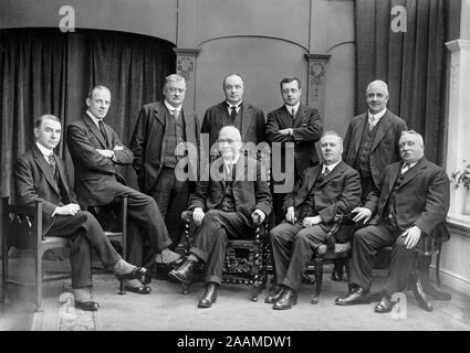 Un inizio di Edwardian inglese vintage fotografia in bianco e nero che mostra un gruppo di uomini, alcuni seduti, alcuni in piedi, in interni. Mostra la moda del periodo. Foto Stock