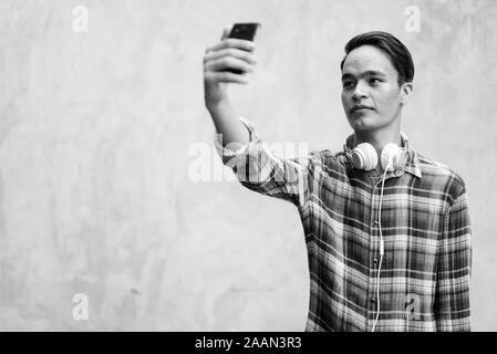 Bel giovane uomo indiano contro il muro di cemento all'esterno in bianco e nero Foto Stock