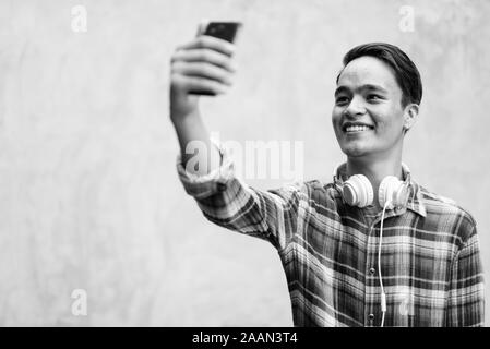 Bel giovane uomo indiano contro il muro di cemento all'esterno in bianco e nero Foto Stock