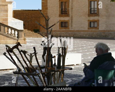 Un uomo Vendita di bastoni da passeggio sotto un albero Foto Stock