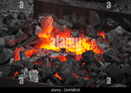 Embers glow in una fucina di ferro nelle tenebre. Incendio, calore, carbone e cenere. Foto Stock